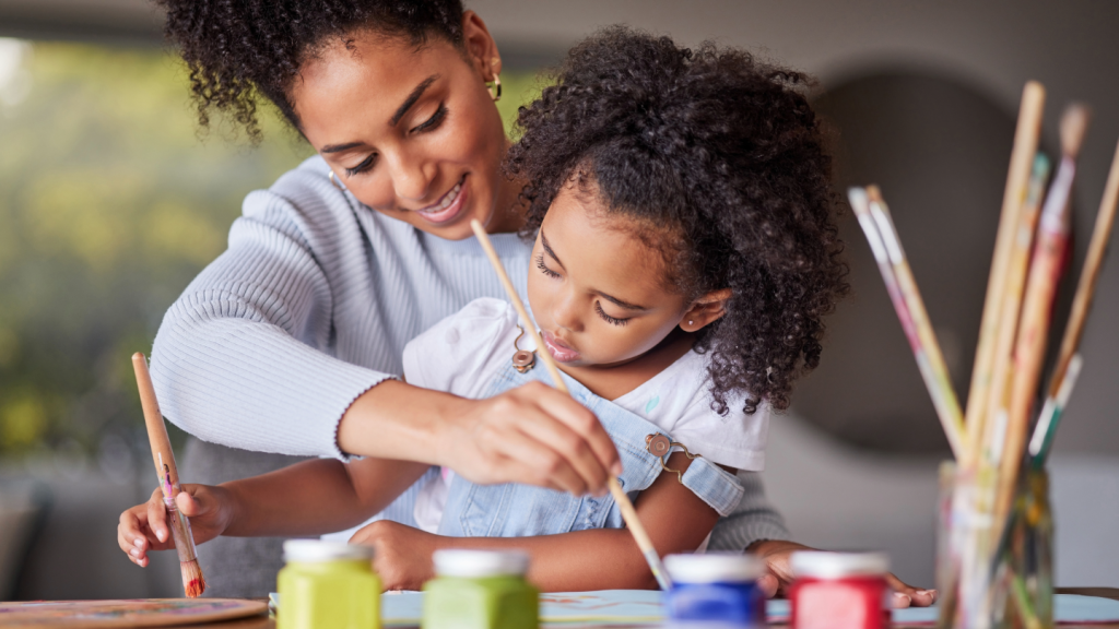A woman and a child paint together at a table.