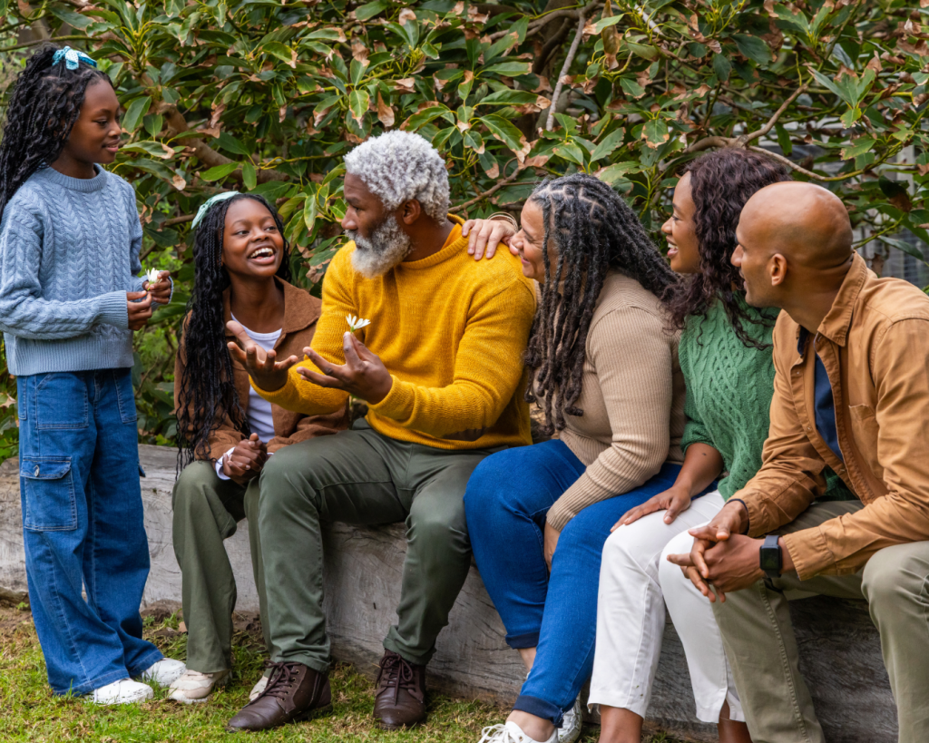 A multigenerational family sits and laughs together while outside.