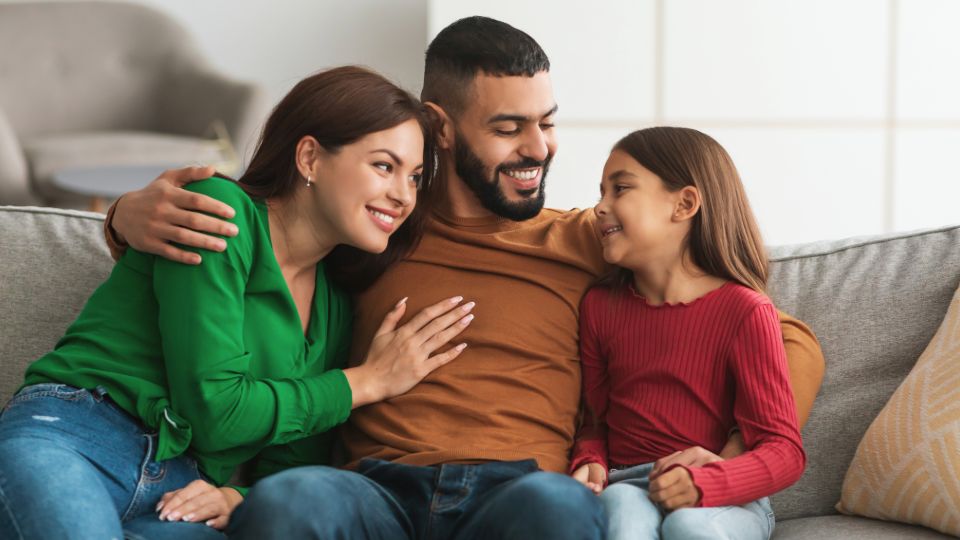 A family sits together on a couch.