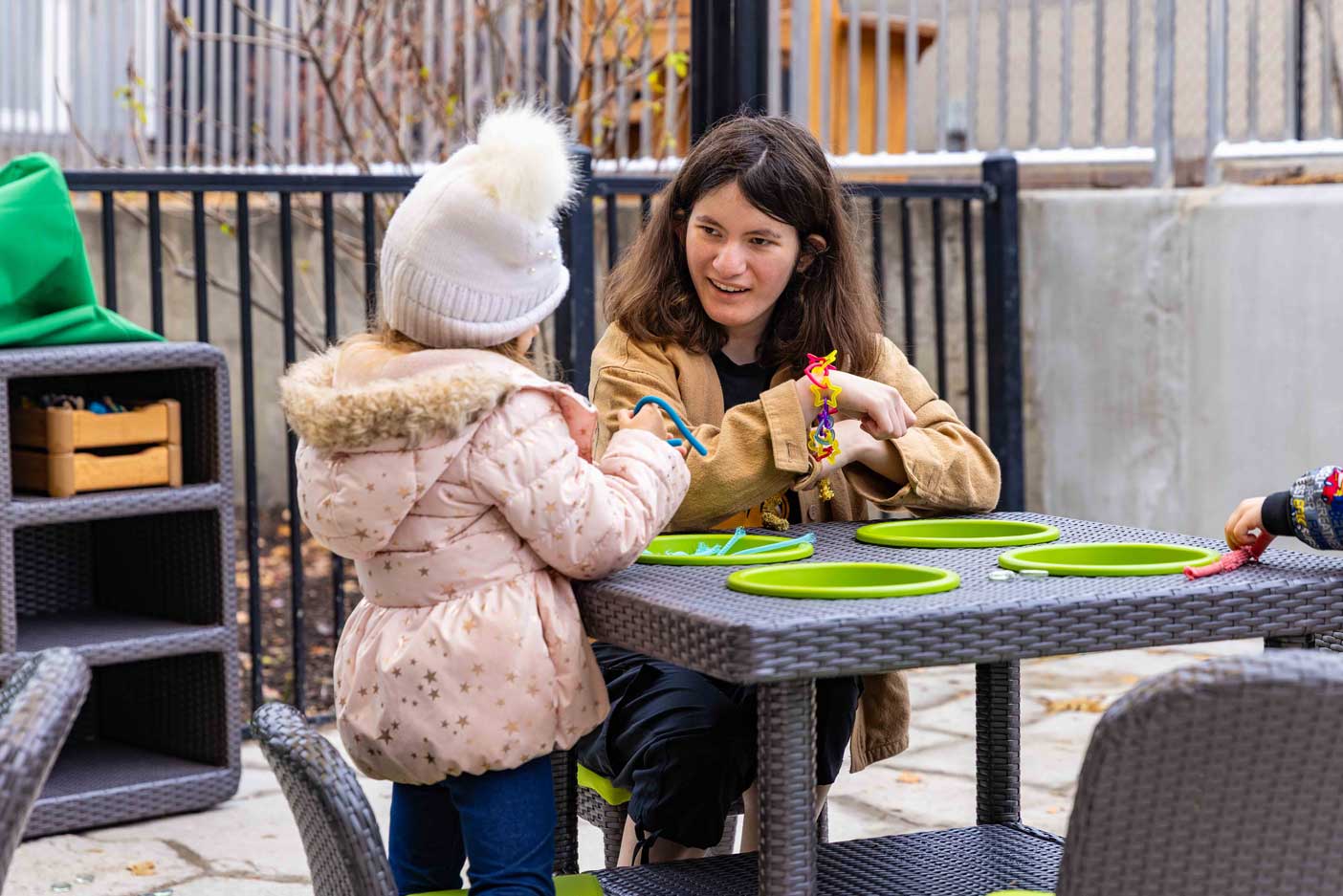 A young child and an early childhood professional work in an outdoor classroom.